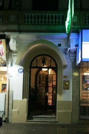 Una entrada de edificio con un arco sobre la puerta y un letrero verde sobre el acceso.