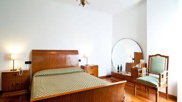 Un dormitorio con cama de madera, mesitas de noche, una silla, un espejo y una araña.
