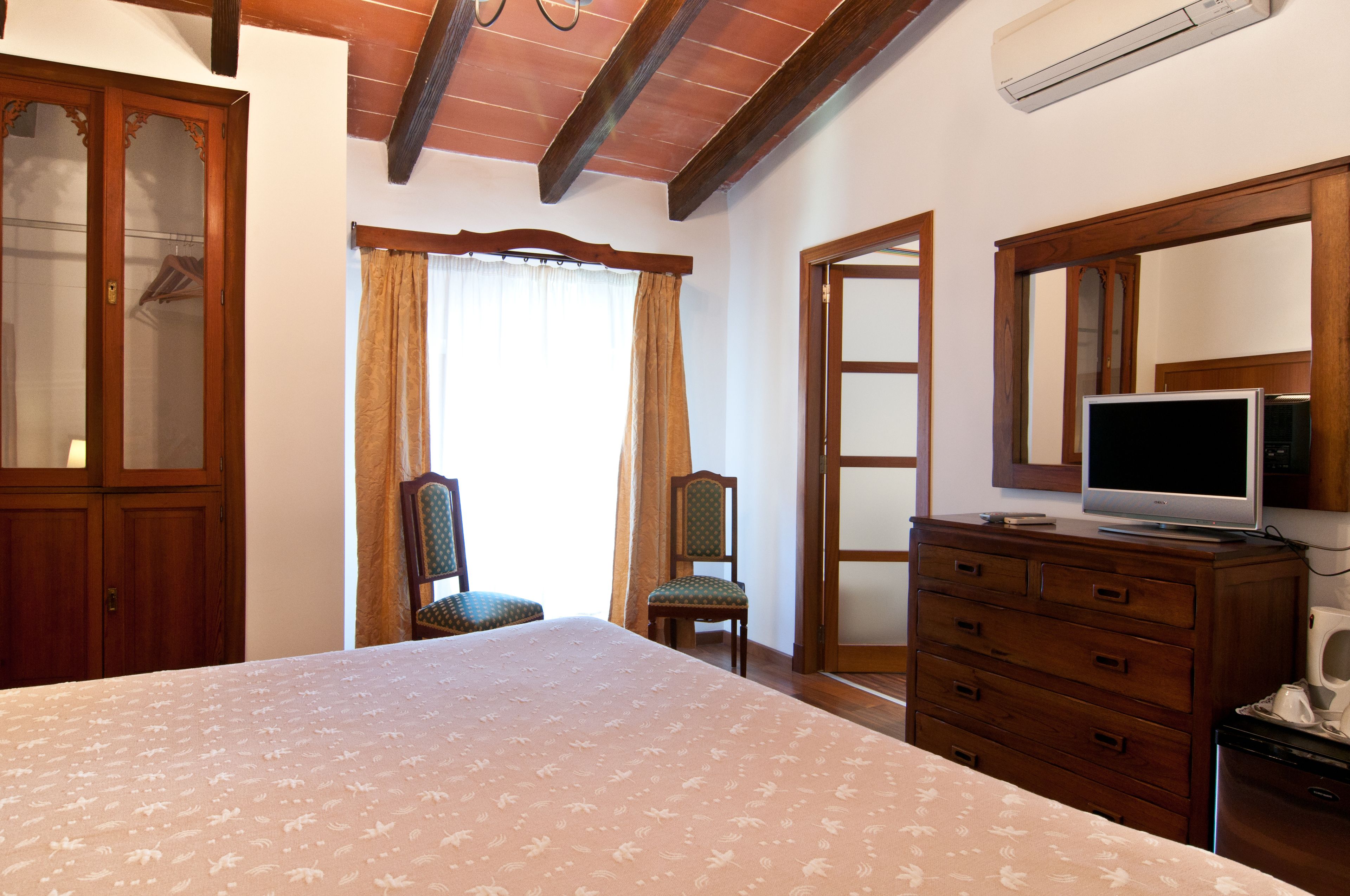 Un dormitorio con cama, cómoda, televisor y silla.