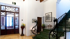 A staircase with a black metal railing and a potted plant beside it.