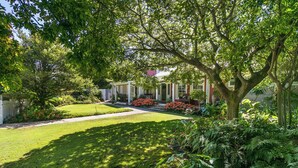 Um jardim bem cuidado com gramado, diversas plantas e um edifício com varanda.