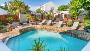 Piscina com espreguiçadeiras e plantas em vasos em um ambiente de quintal.