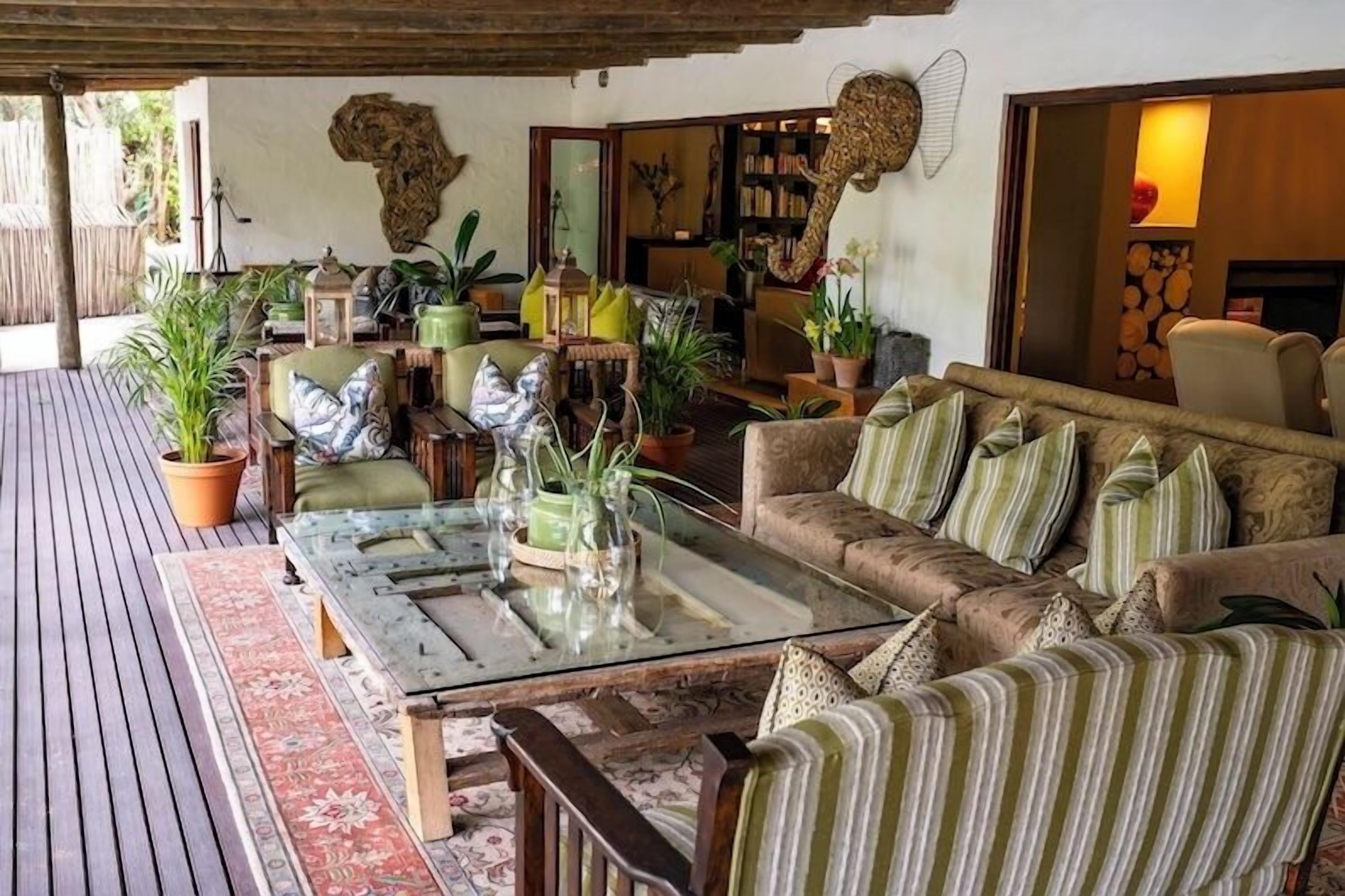 A cozy outdoor seating area with a wooden deck, cushioned sofas, and potted plants.
