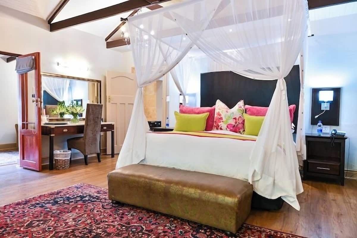 A bedroom with a canopy bed, a desk, and a chair.
