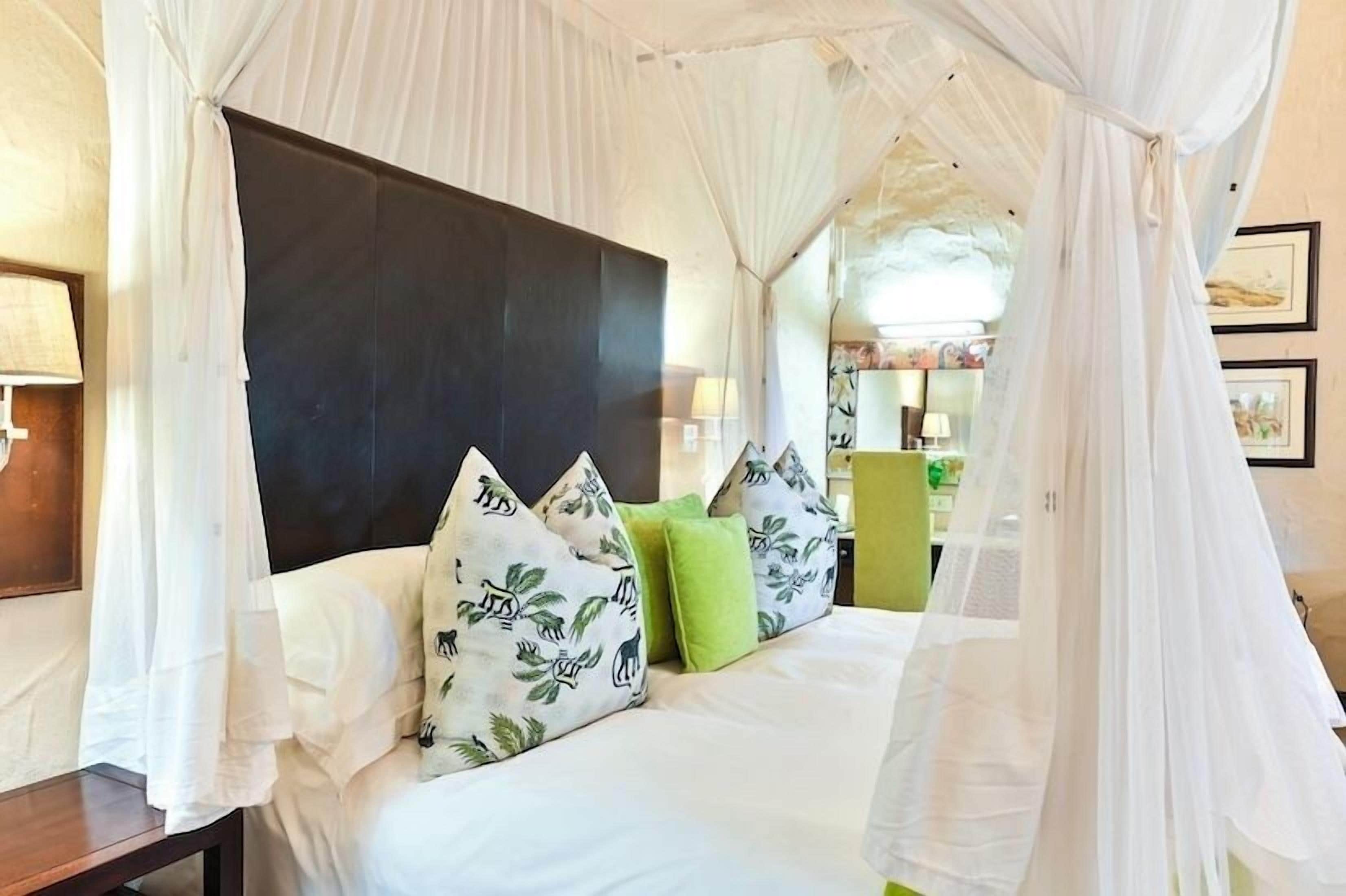 A bed with a canopy, a dark headboard, and patterned pillows.