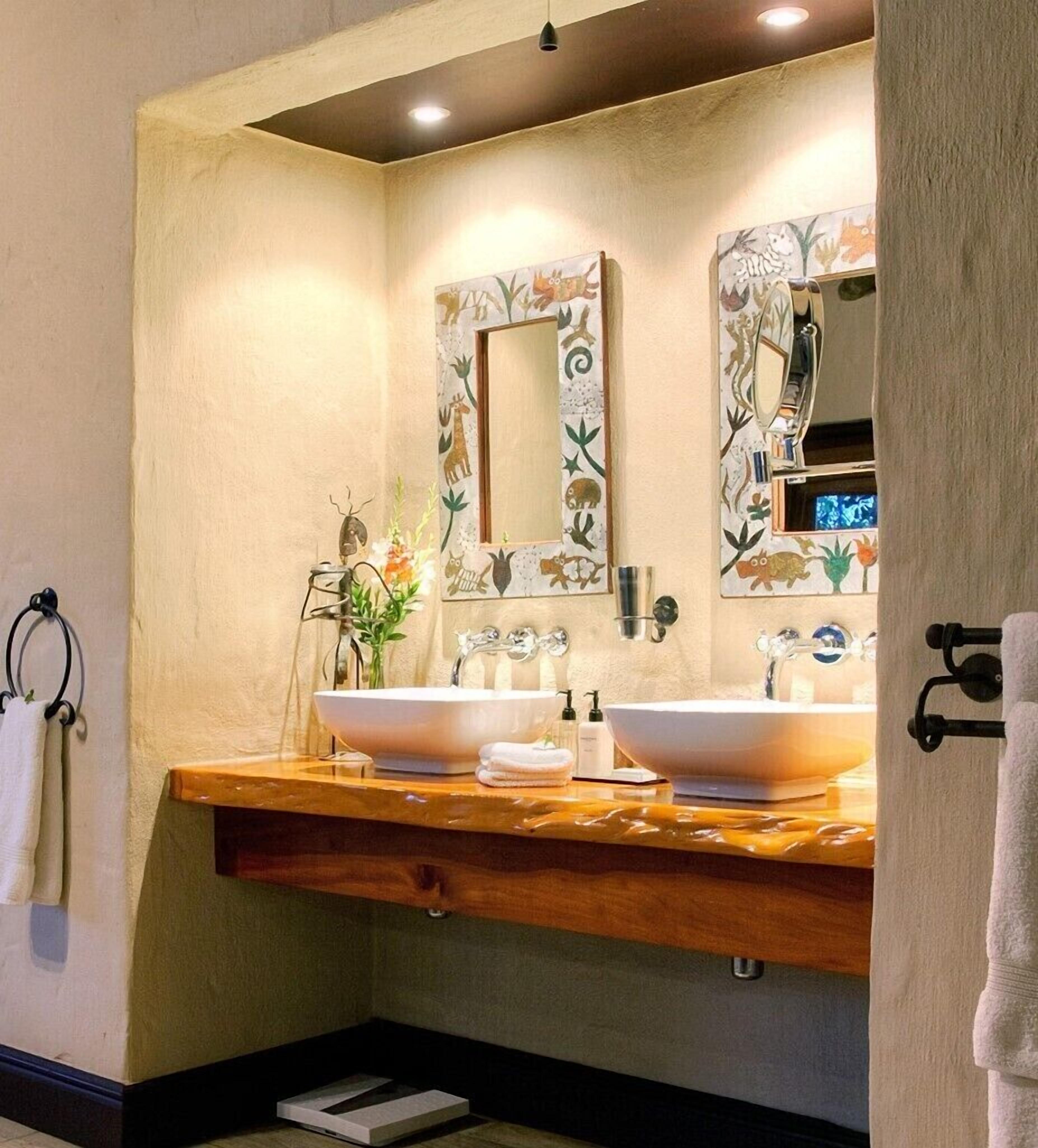 A bathroom with two sinks, a wooden vanity, and a mirror with a decorative frame.
