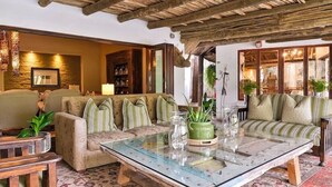 Un salon chaleureux avec un plafond en bois, une table basse en verre et des canapés à rayures.