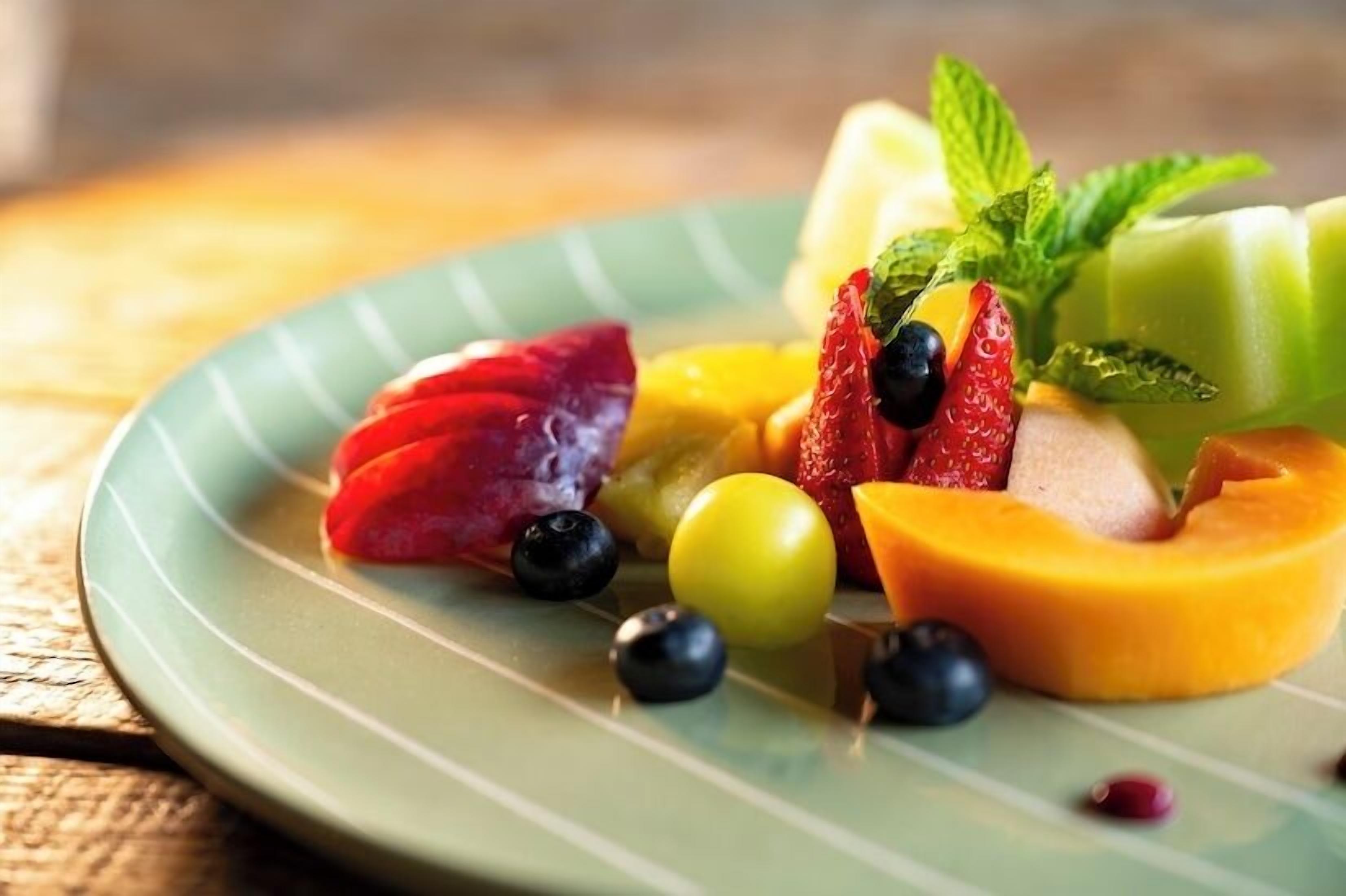 Um prato com frutas fatiadas e um raminho de hortelã.