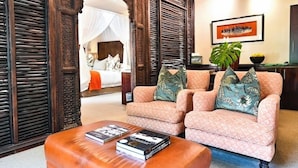 Une pièce comprenant un lit, deux fauteuils, une table basse et un tableau au mur.