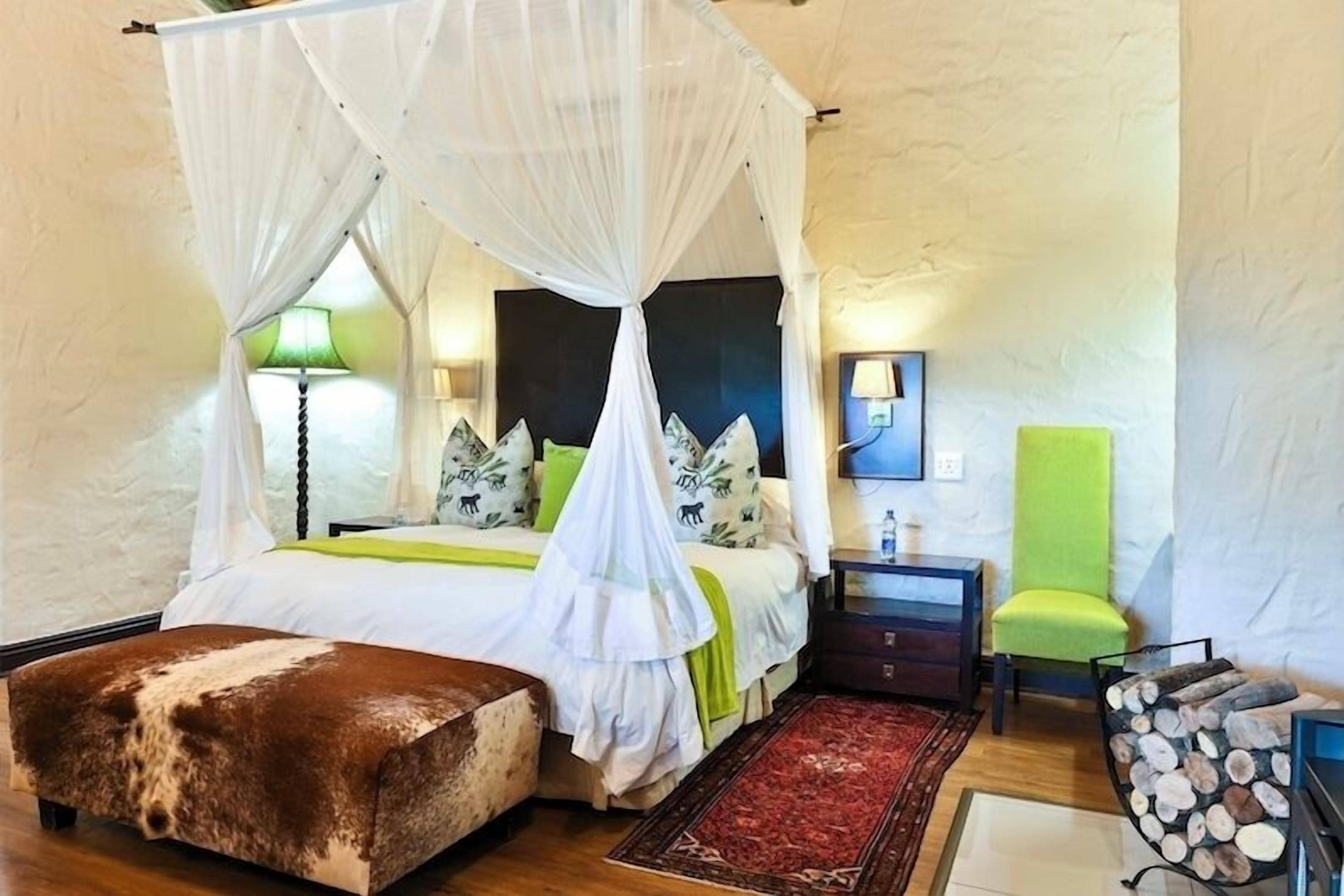 A bedroom with a four-poster bed, a bedside table, a chair, and a small rug.