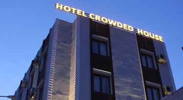 Um edifício com uma placa que diz 'HOTEL CROWDED HOUSE'.