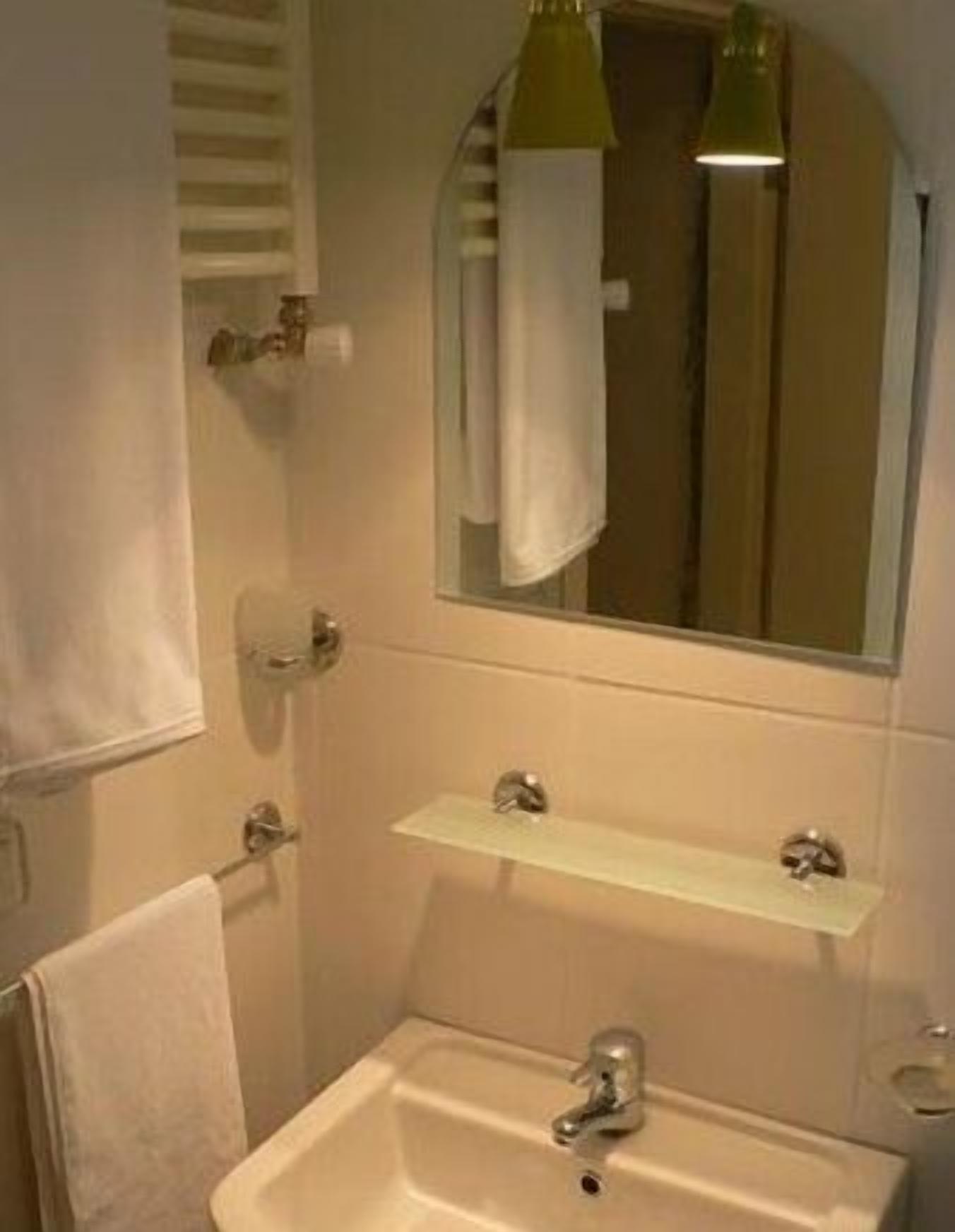 A bathroom with a sink, mirror, towel rack, and a towel hanging on the wall.