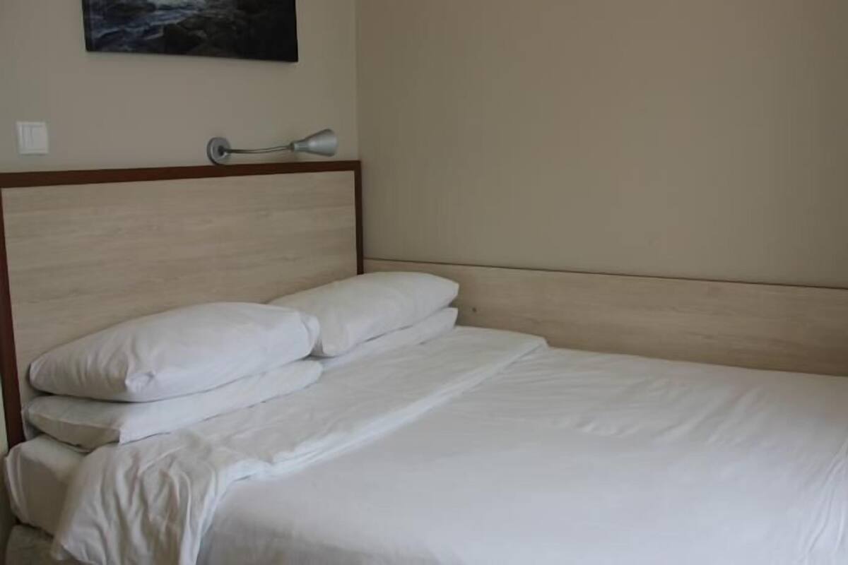 A neatly made bed with white linens in a hotel room.