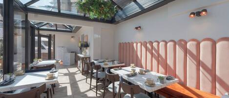 A restaurant with a glass ceiling, tables with chairs, and hanging plants.
