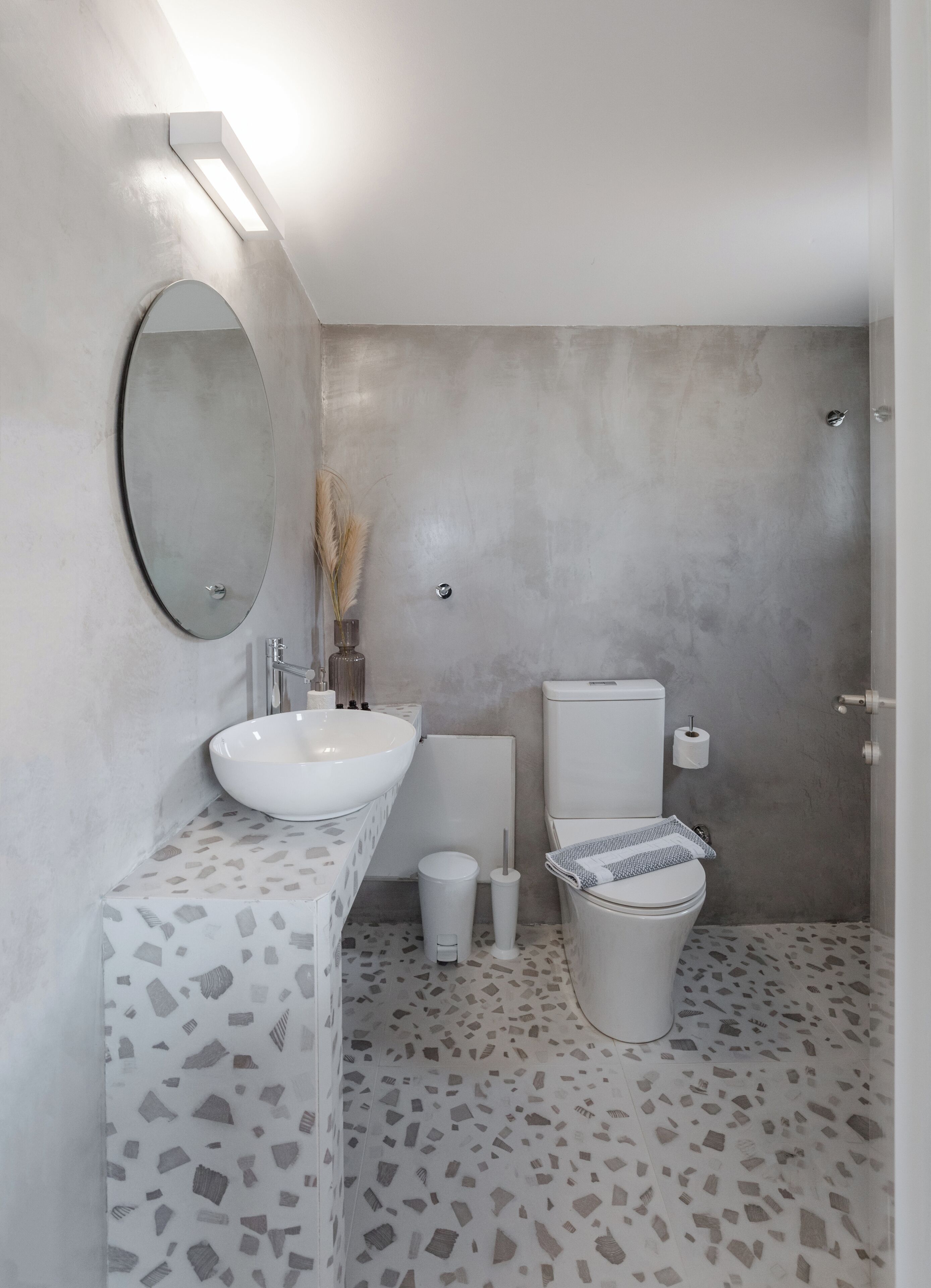 Un bany modern amb un gran mànec oval, un vàter i un bidet. El terra té un disseny de terrazzo.