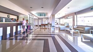 Un vestíbulo amplio con una recepción, zona de estar y mostrador de registro.