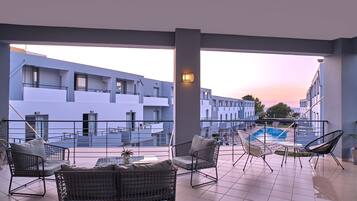 Une terrasse dotée de meubles en osier, une piscine et une vue sur un bâtiment moderne.