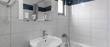 A bathroom with a sink, mirror, and shower.