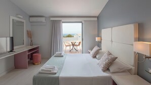 Habitación de hotel con cama, mesitas de noche, televisión, escritorio, silla y balcón con mesa y sillas, además de un aire acondicionado.