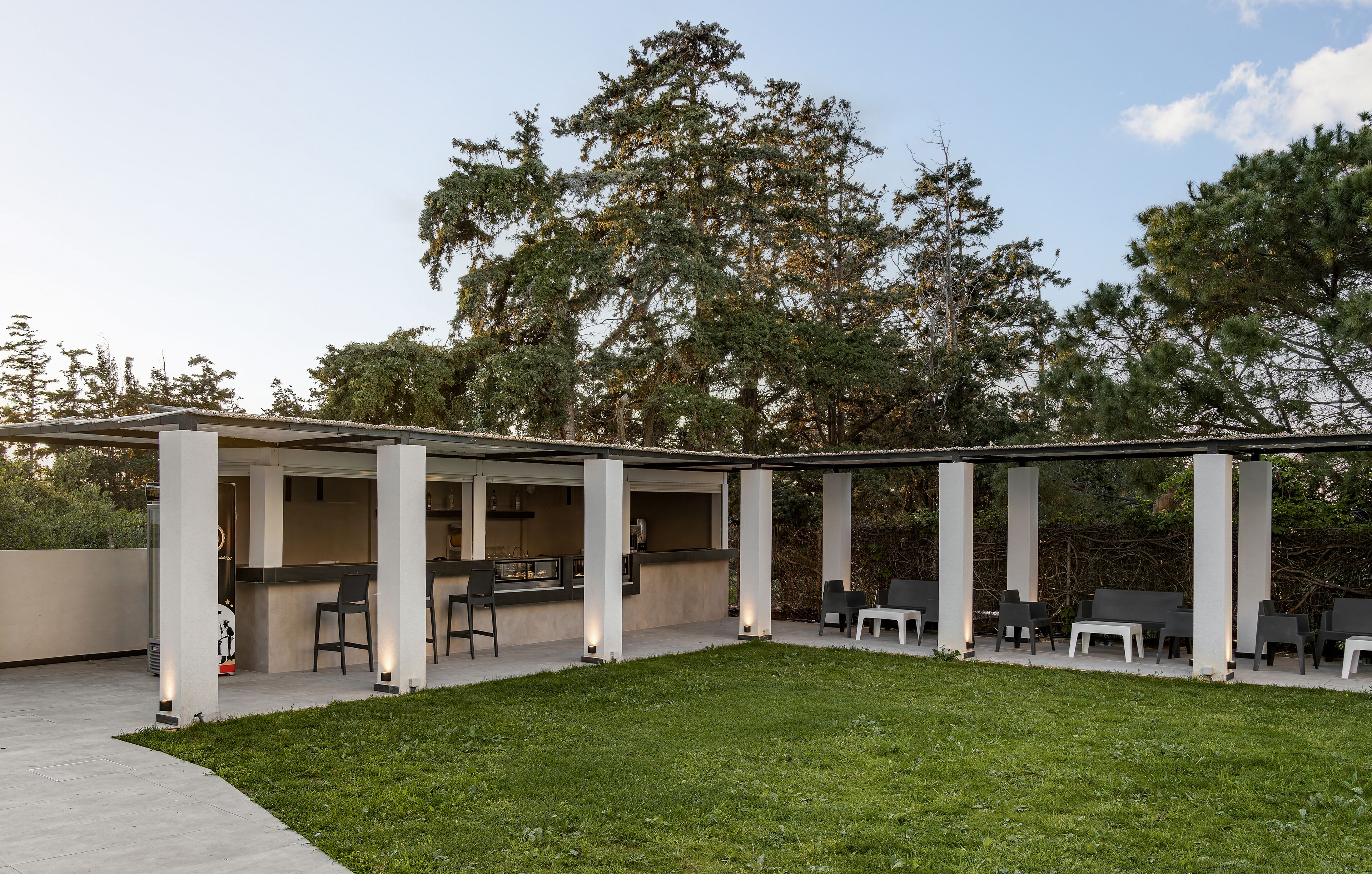 Une terrasse extérieure dotée d’un espace salon couvert, d’un bar et d’une pelouse.