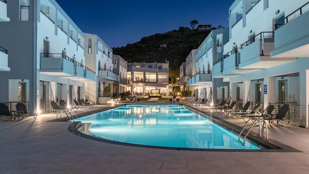 Un hotel moderno con piscina, varios balcones y vistas a una colina.