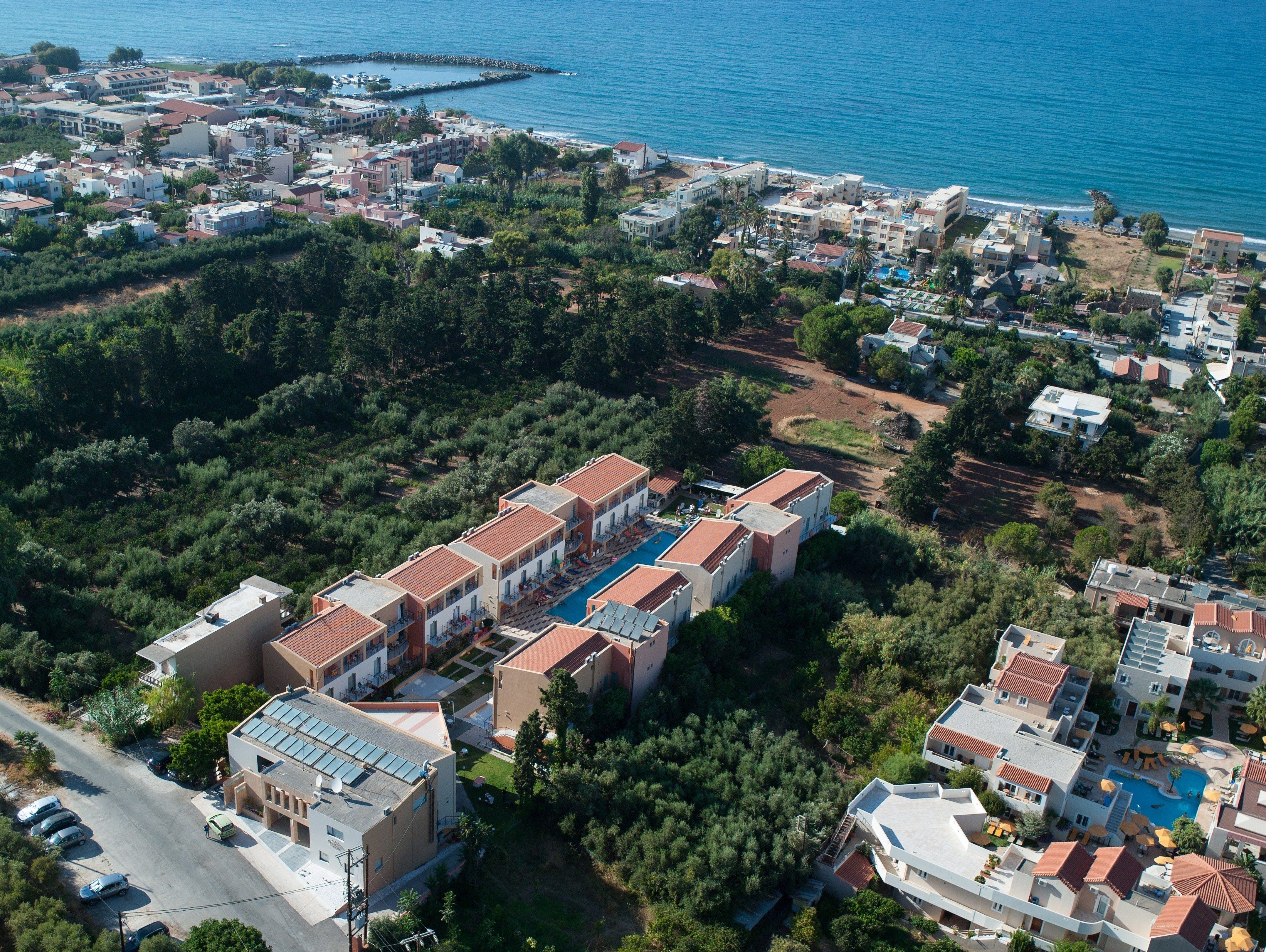An aerial view of a coastal resort with multiple buildings, a swimming pool, and a marina.