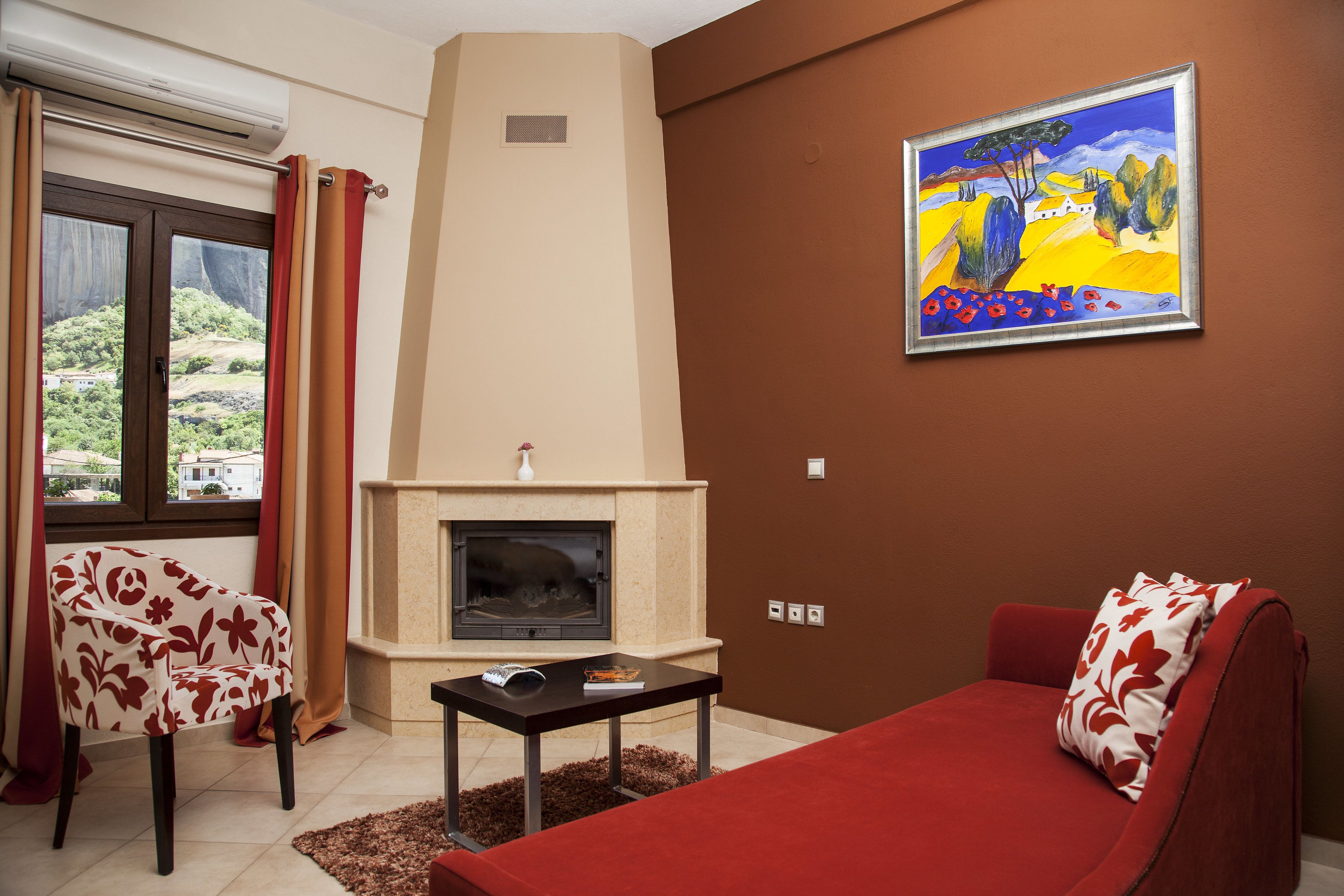 Ein Wohnzimmer mit Kamin, einer Couch, einem Sessel und einem Bild an der Wand.