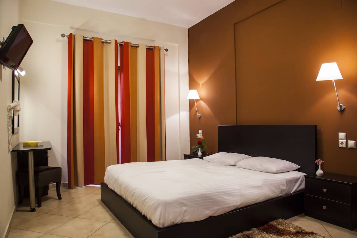 A bedroom with a bed, bedside tables, a desk, and a chair.