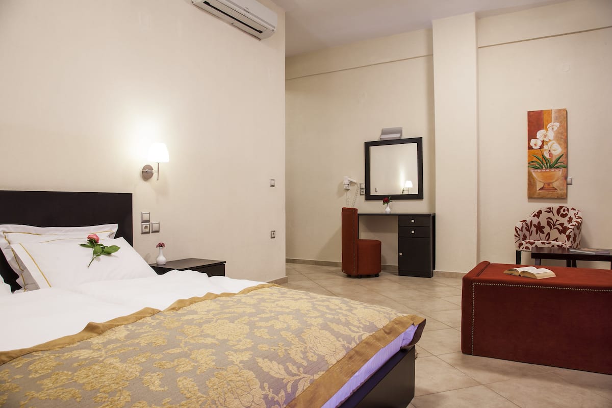A hotel room with a bed, bedside table, desk, chair, and artwork on the wall.