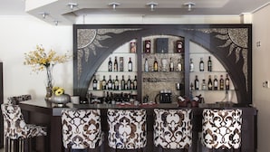 A bar area with a dark counter, patterned bar stools, and a variety of bottles and glasses. - Meteoritis Hotel (Kalabaka)