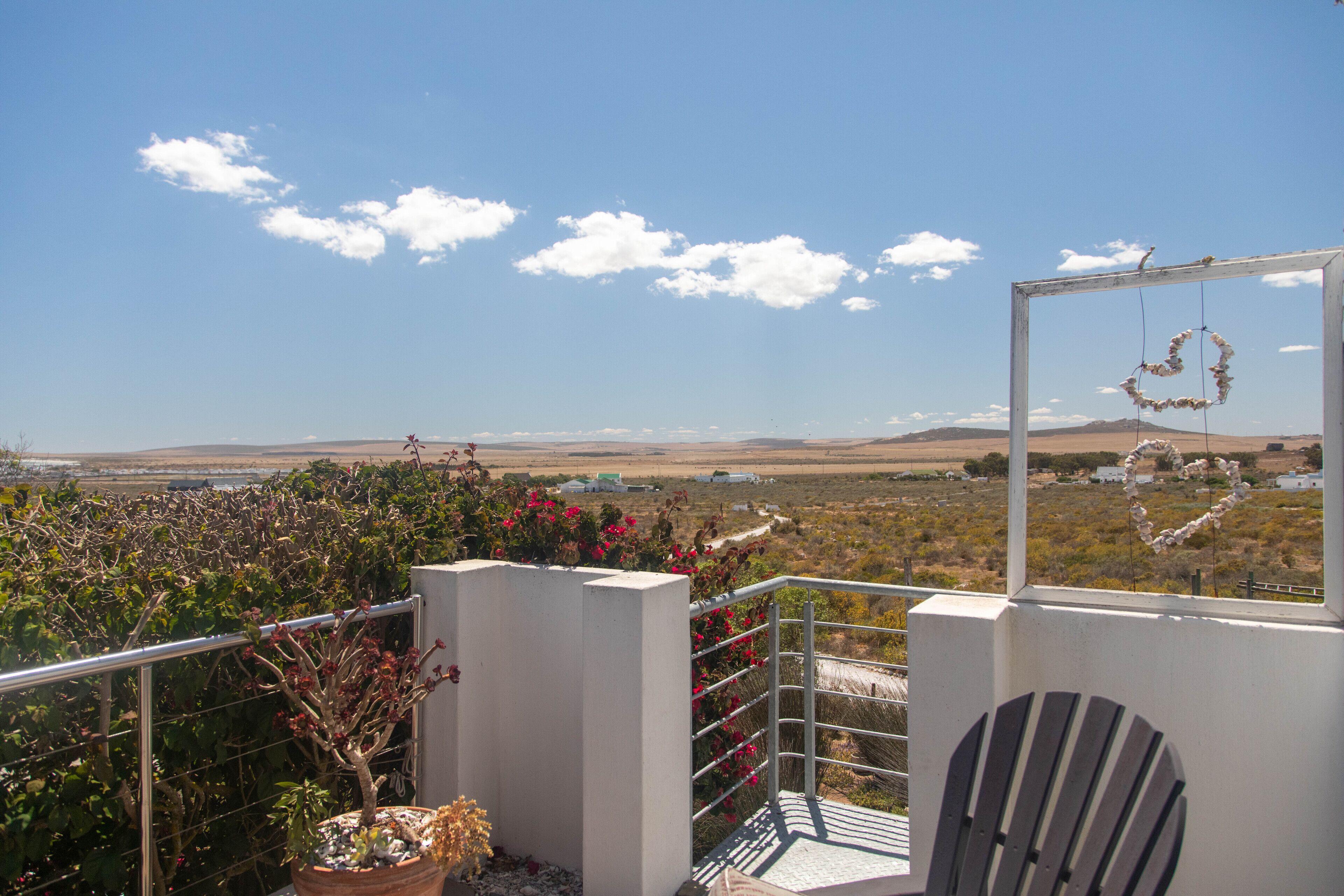 Un balcón con vistas a un paisaje rural, una planta en maceta y una silla.