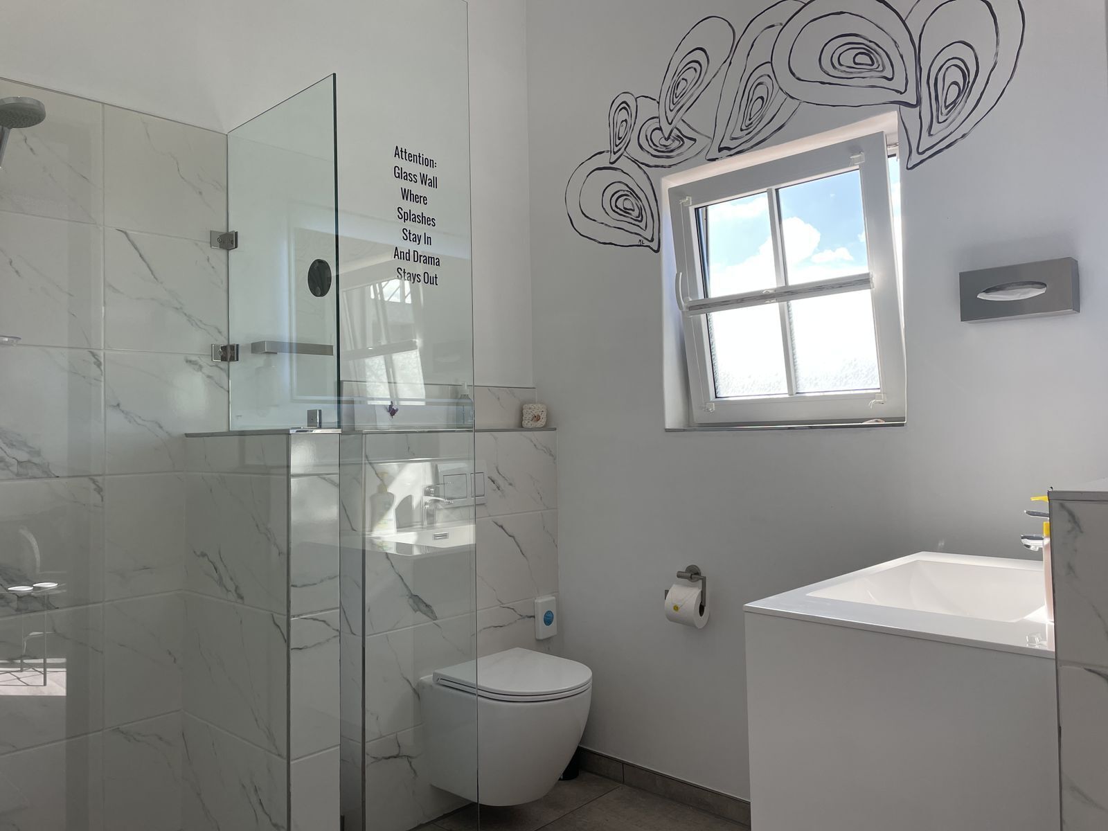 A bathroom with a glass shower enclosure, a toilet, and a sink.