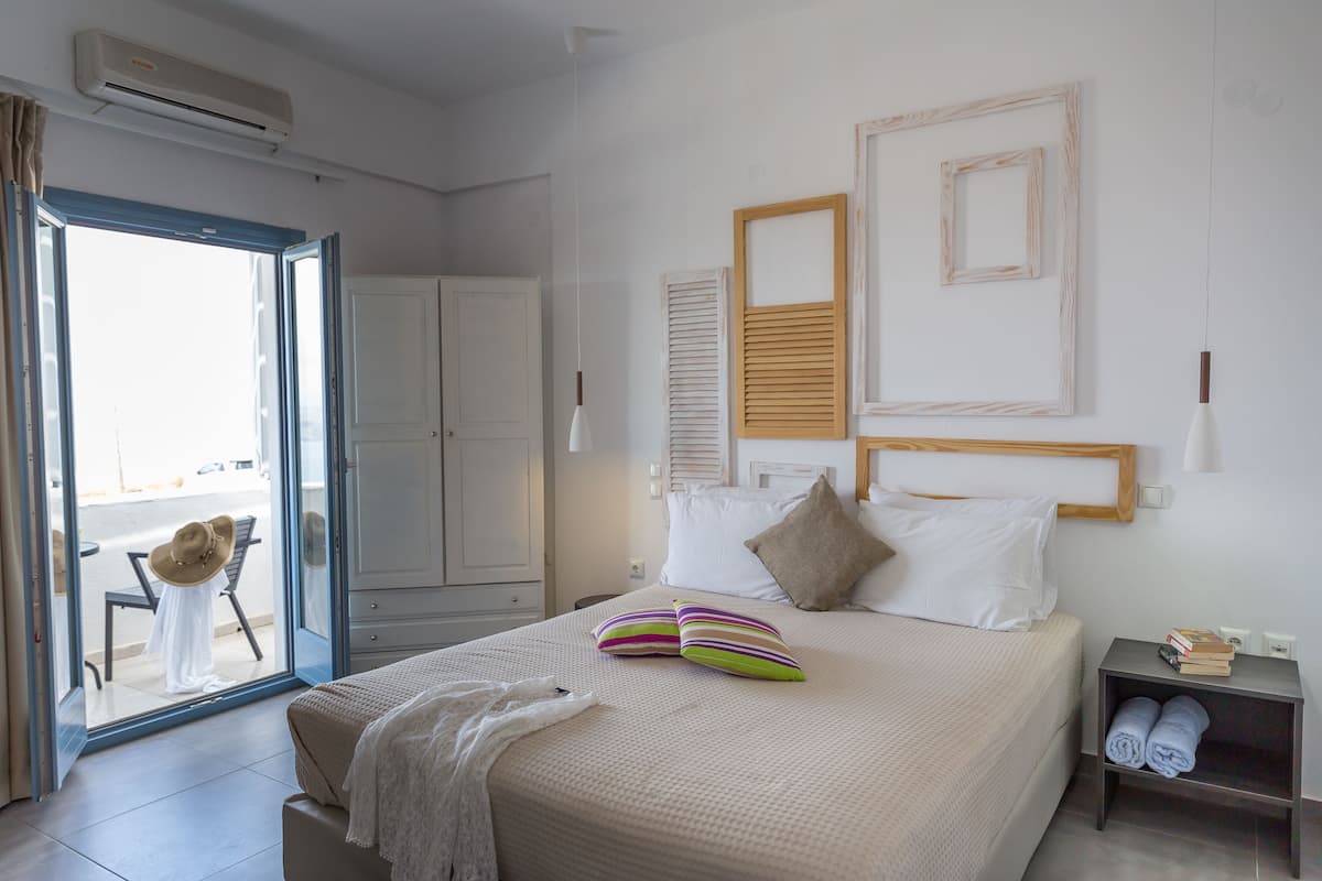 A bedroom with a bed, pillows, a nightstand, and a view through a glass door.