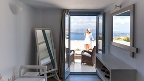 A room with a sliding glass door leading to a balcony with a view of the sea and mountains. - Caldera Romantica (Santorini)
