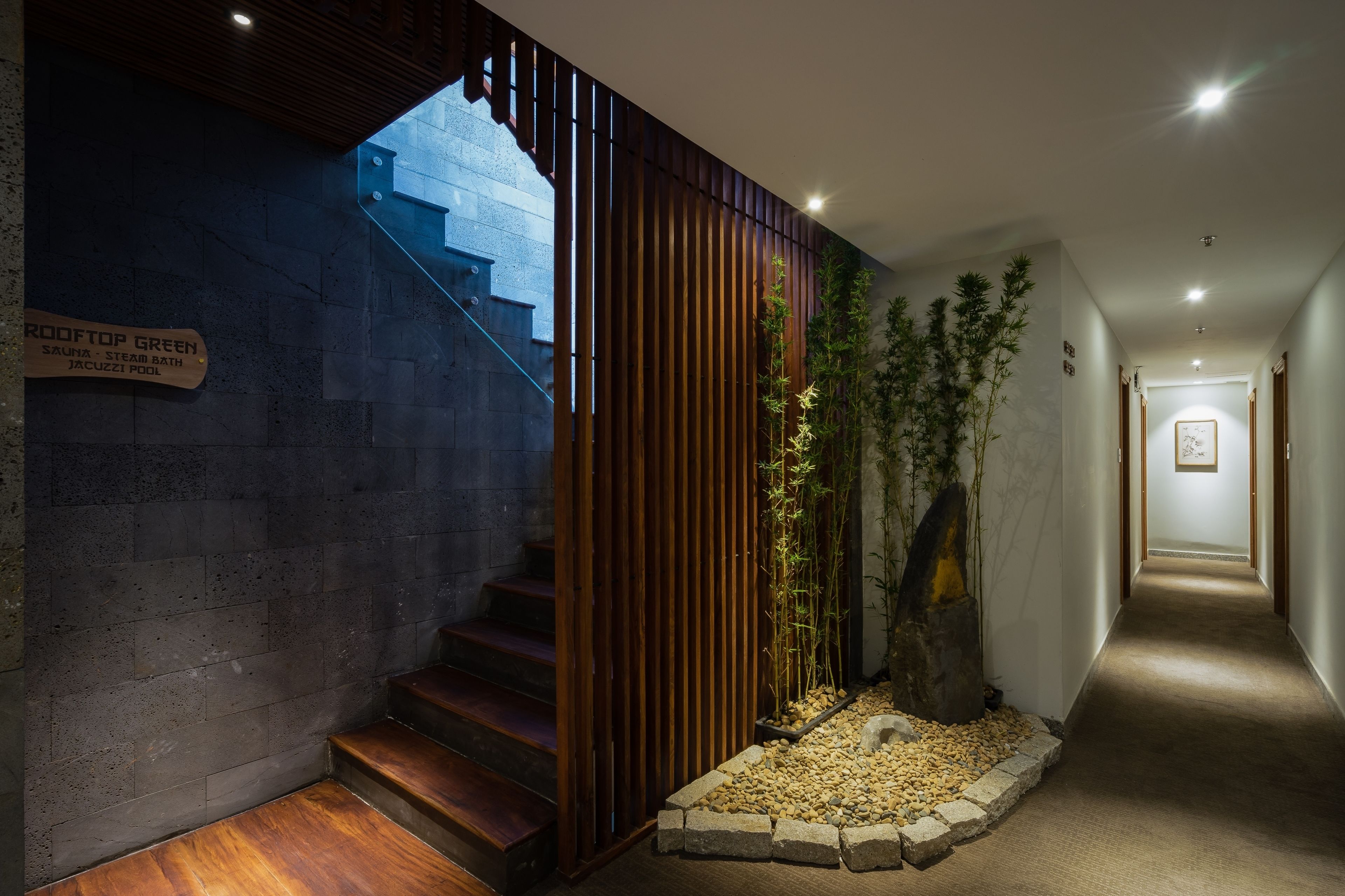 A modern interior with a staircase leading to a rooftop green area, including a steam bath and jacuzzi pool.