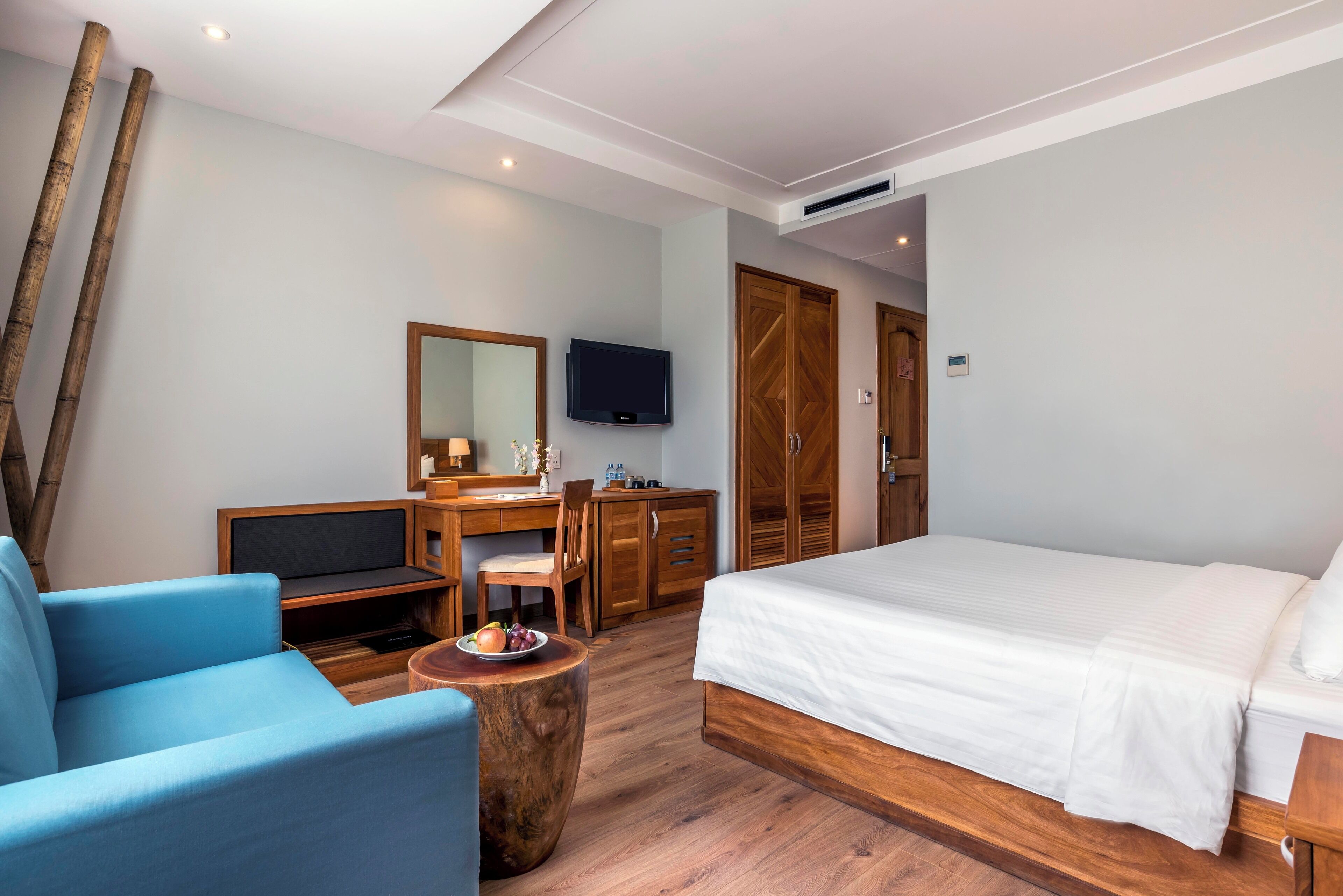A modern bedroom with a large bed, a desk with a chair, a television, and a wardrobe.