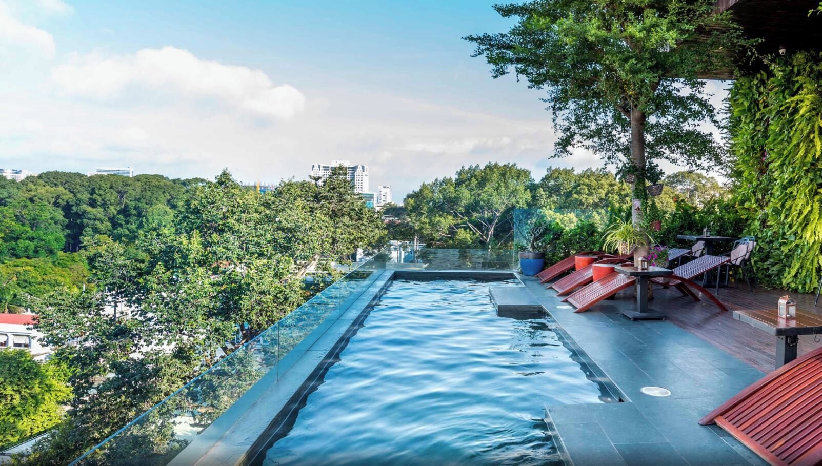 A rooftop infinity pool with a clear view of the cityscape and lush greenery.
