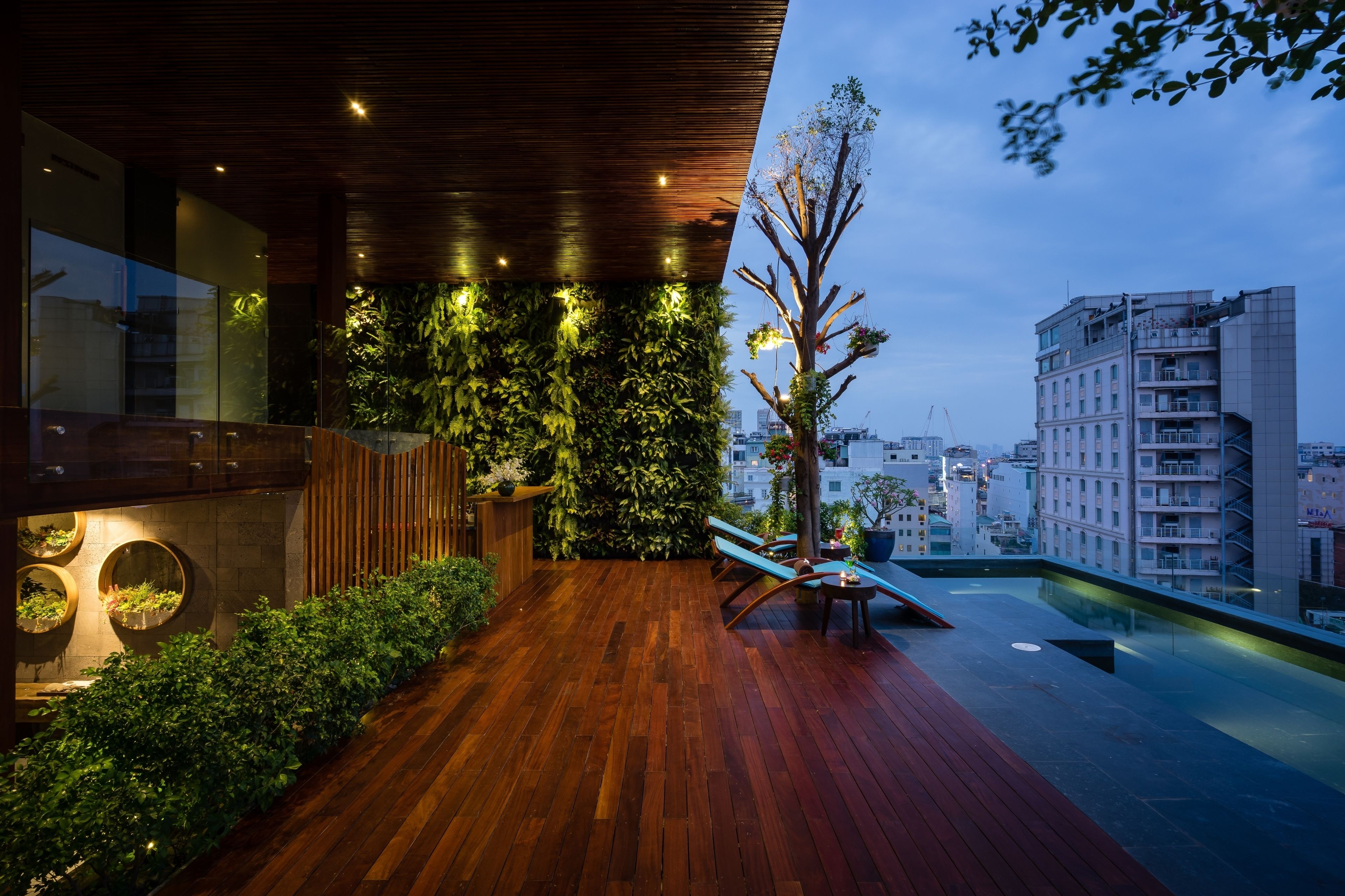 A rooftop terrace with wooden flooring, vertical gardens, and a seating area.
