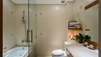 A modern bathroom with a glass-enclosed shower, a white toilet, and a marble sink.