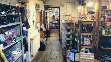 A narrow, rustic shop with wooden shelves and displays of various items including handbags, jewelry, and other accessories.