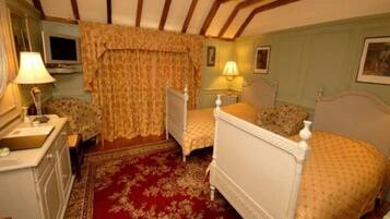 A room with a bed, bedside table, lamp, and a red patterned carpet.