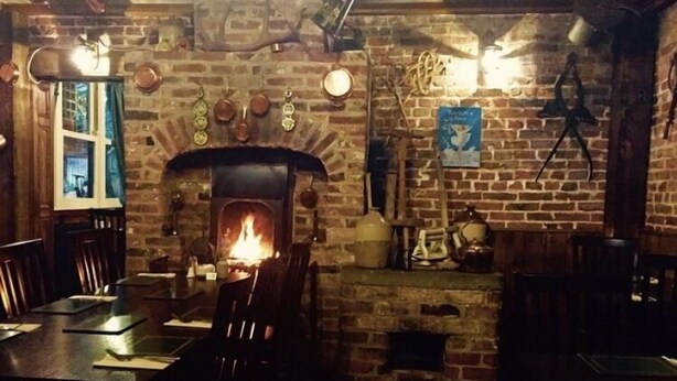 A rustic interior with a brick fireplace, wooden furniture, and a stone wall. - Wolds Village (Driffield)