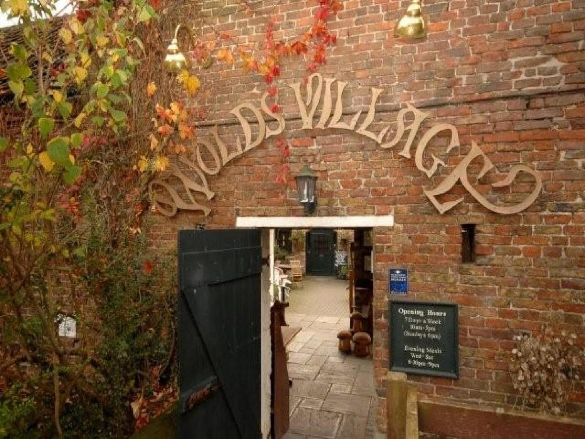 A brick building entrance with a sign reading 'Woods Village.'