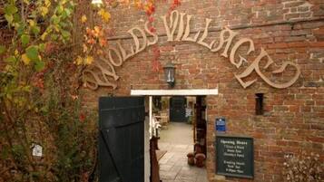 A brick building entrance with a sign reading 'Woods Village.'