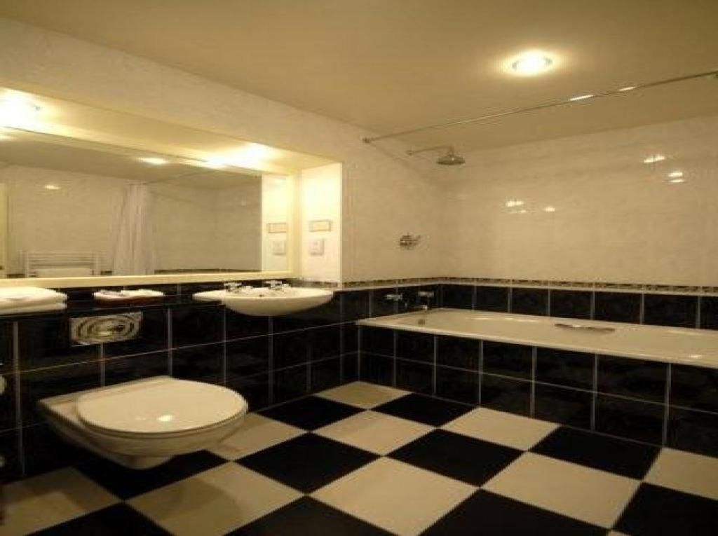 A bathroom with a checkered floor, a toilet, a sink, and a bathtub.