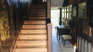 A wooden staircase leading to a room with a dining table and chairs, a vase, and framed pictures on the wall. - Wolds Village (Driffield)