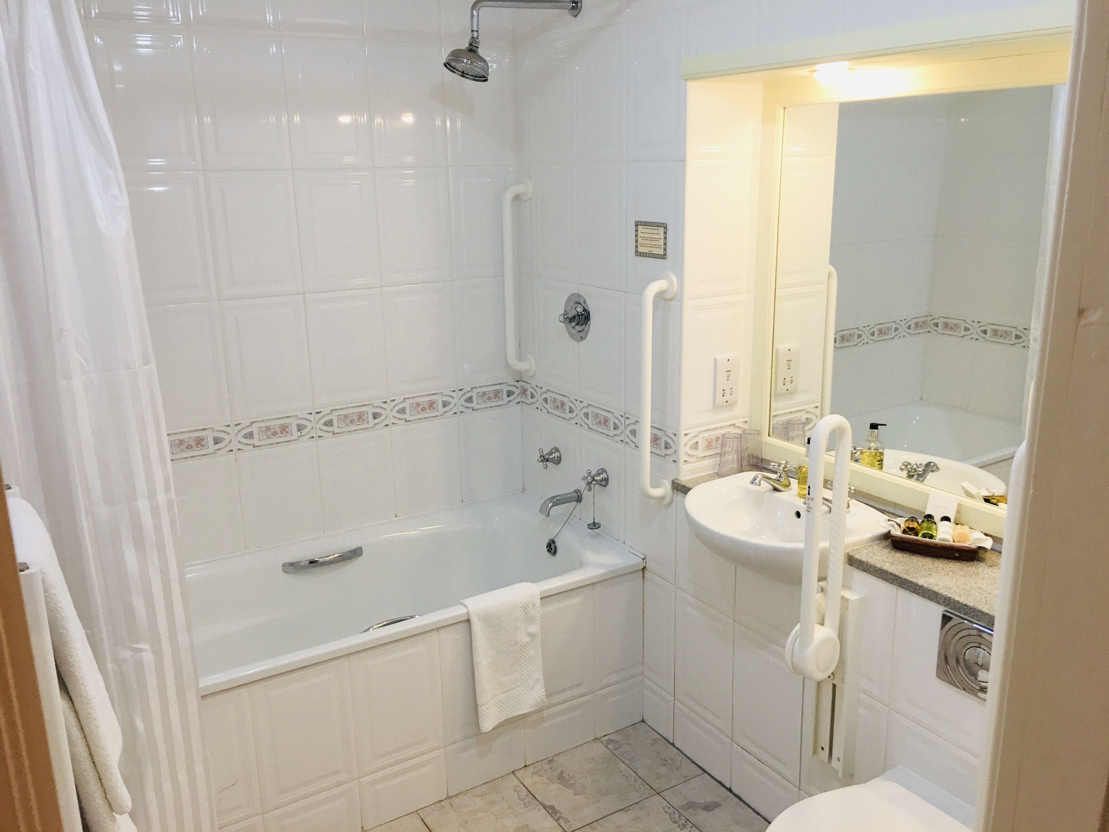 Een badkamer met een bad, wastafel, spiegel en douche.