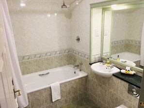 Un baño con bañera, lavamanos y espejo.