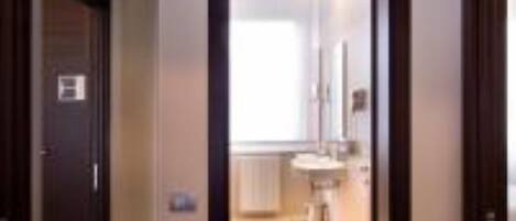 A hallway leading to a bathroom with a sink and mirror.