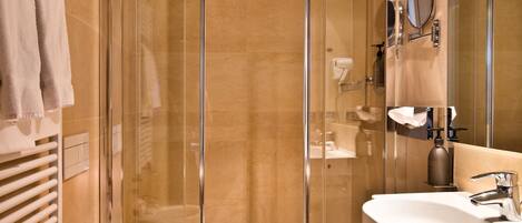 Un baño moderno con ducha de vidrio, un bidé y un lavamanos con espejo.